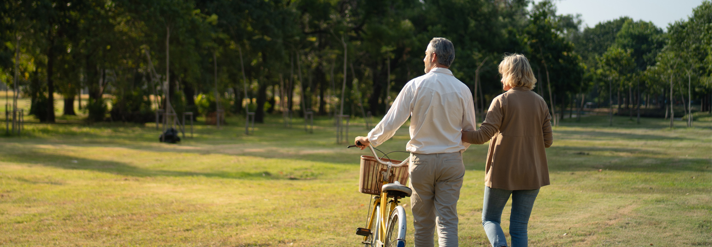  Pareja de esposos caminan por un campo con una bicicleta a su lado.