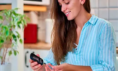 Mujer joven, tranquila, monitoreándose la glucosa en la sangre.