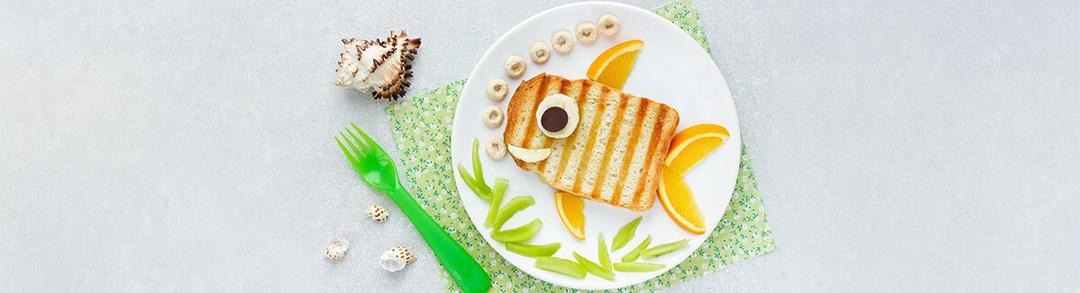 La imágen muestra una comida con forma de pescado formato con un pan tostato y aletas de naranjas