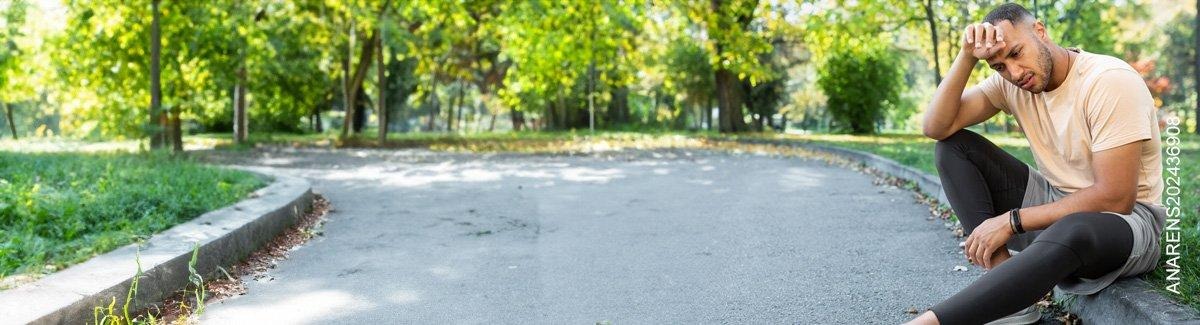 Hombre sentado en un andén con ropa de ejercicio