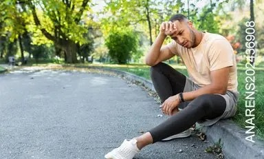 Hombre sentado en un andén con ropa de ejercicio