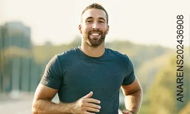 Hombre sonriendo trota por una carretera