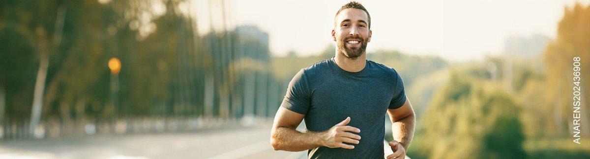 Hombre sonriendo trota por una carretera
