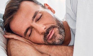 Hombre con barba duerme plácidamente en su cama