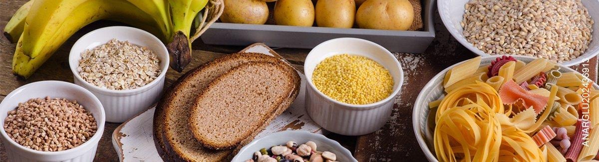 Mesa con diferentes carbohidratos servidos, pan, frijoles, papa, pastas, avena.