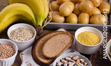 Mesa con diferentes carbohidratos servidos, pan, frijoles, papa, pastas, avena.