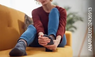  Mujer sentada en un sofá sujetando su pie