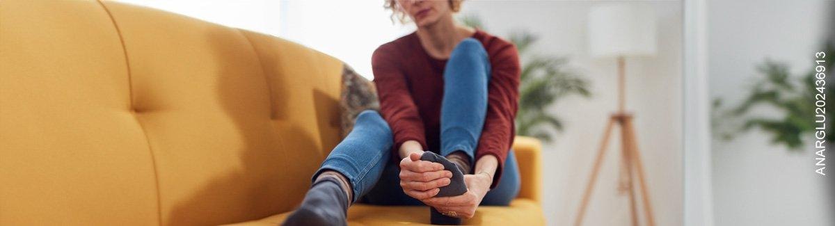  Mujer sentada en un sofá sujetando su pie