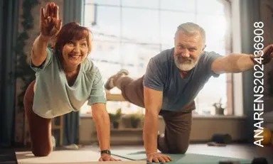 Pareja de adultos sonrientes practica yoga en la sala de su casa